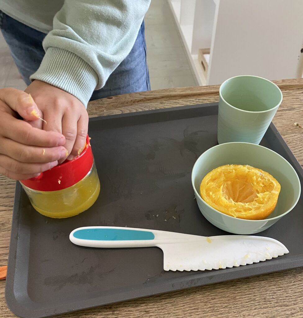 enfant pressant une orange sur un presse agrume